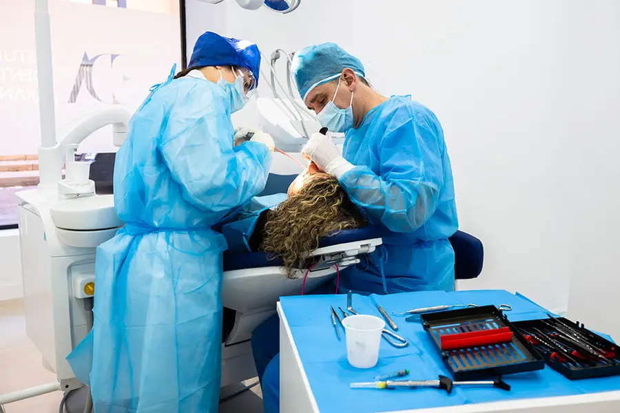 Two surgeons operating, with a tray of surgical instruments in front