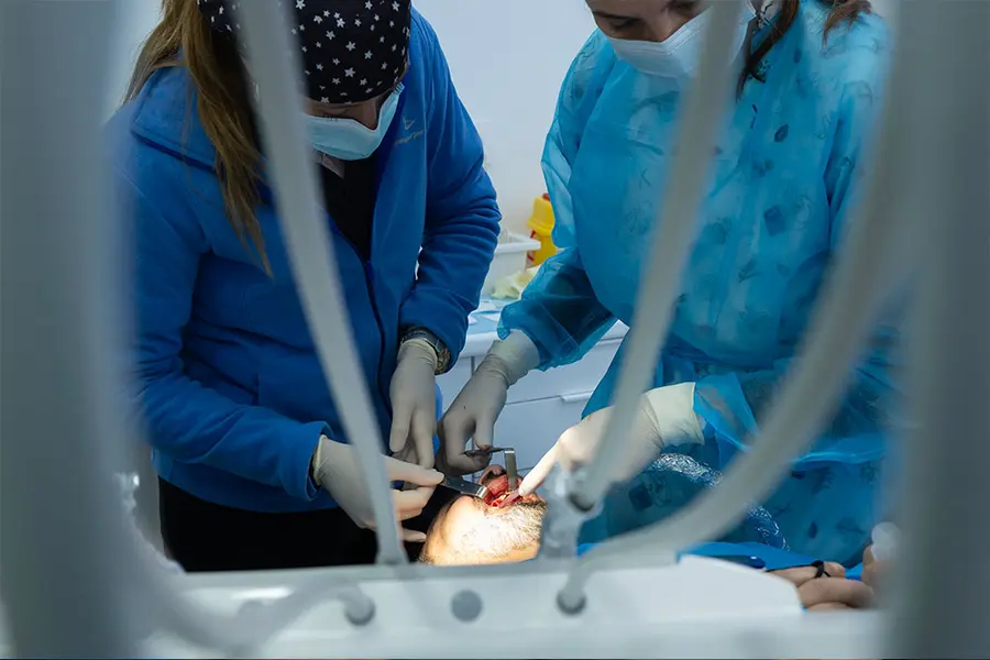 Two clinicians working on a patient, seen from behind the headrest